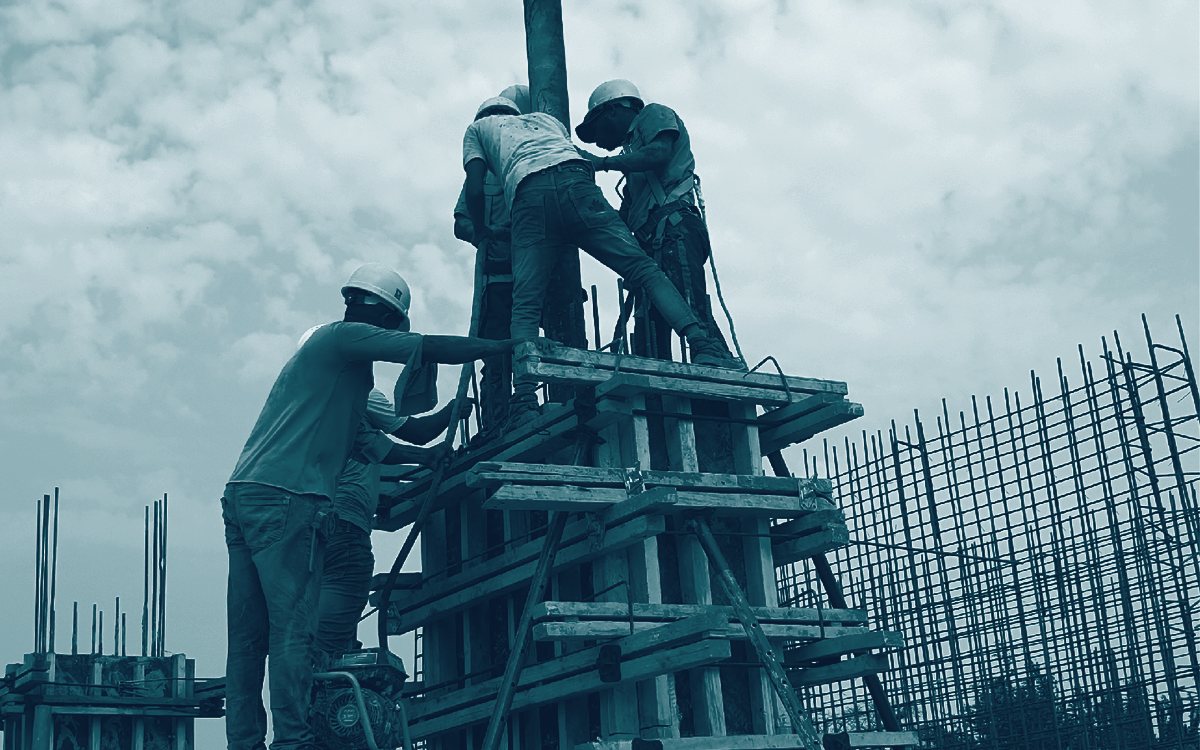 Workers on scaffolding assembling formwork for a reinforced concrete column.