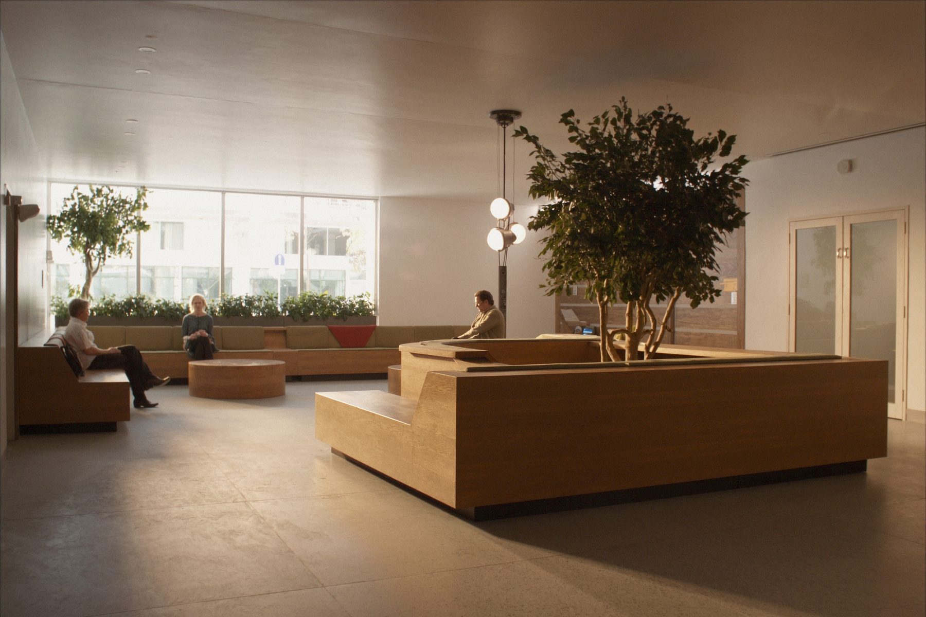 A hospital outpatient waiting area in soft daylight, with people seated.